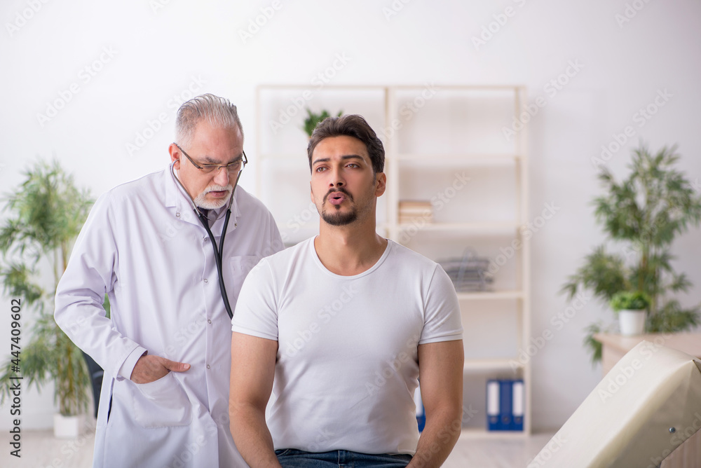 Fototapeta premium Young male patient visiting old male doctor