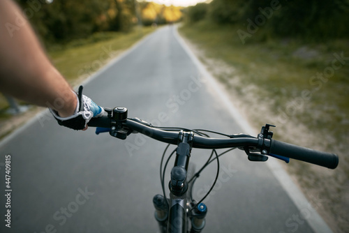 Asphalt bike path for bike riders. Concept of infrastructure for bikers. A cyclist holds a bicycle handlebar with his hand in glove.
