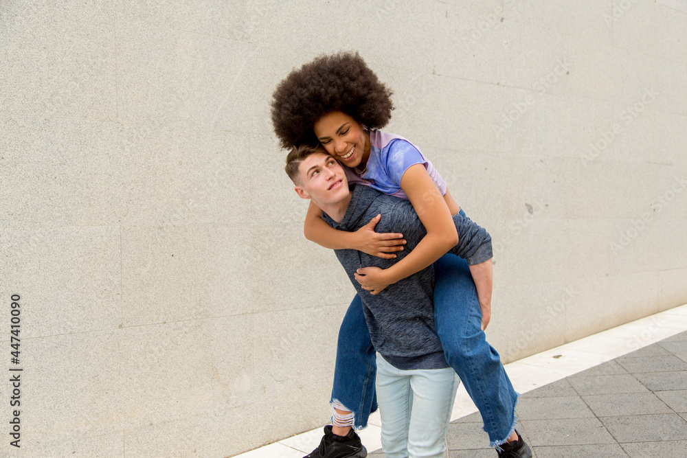 multiethnic couple Caucasian young man carrying afro woman on his back on a sunny day