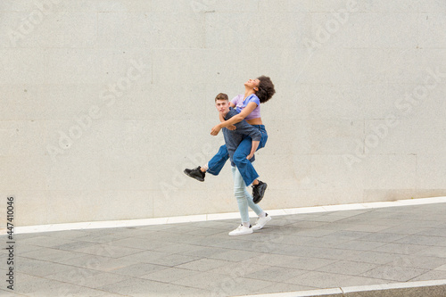 Caucasian young man carrying afro woman on his back having fun
