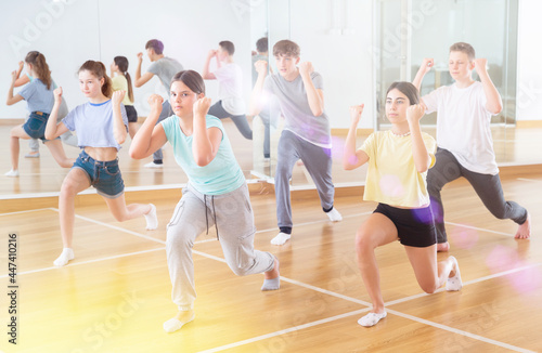 Positive teenage dancers doing dance workout during group class © JackF
