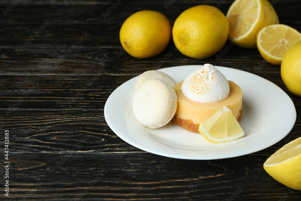 Plate with cupcake and macaroons, and lemons on wooden table Plate with cupcake and macaroons, and lemons on wooden table