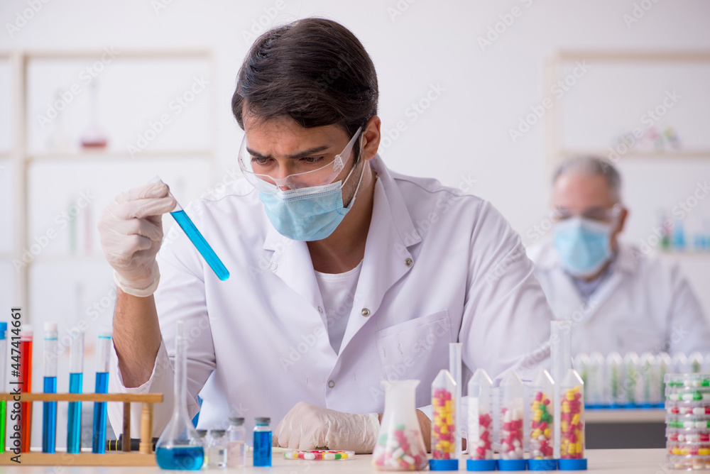 Two male chemists in drugs synthesis concept at the lab Two male chemists in drugs synthesis concept at the lab
