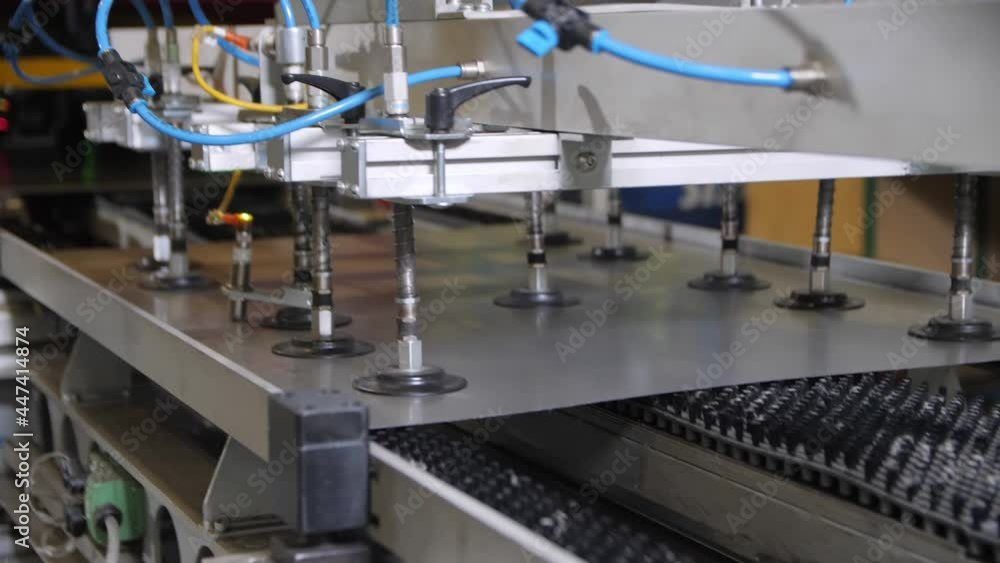 Manipulator with vacuum cups puts metal sheet on production line with conveyor in plant workshop extreme close view Manipulator with vacuum cups puts metal sheet on production line with conveyor in plant workshop extreme close view