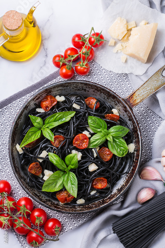 Black spaghetti pasta with tomatoes, cheese and basil