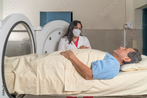 Doctor with a patient on a stretcher in front of a hyperbaric treatment machine