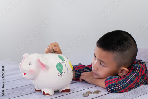 boy putting coin down Money piggy bank elephant sculpture is a way to teach children to save money for the future. boy's creativity