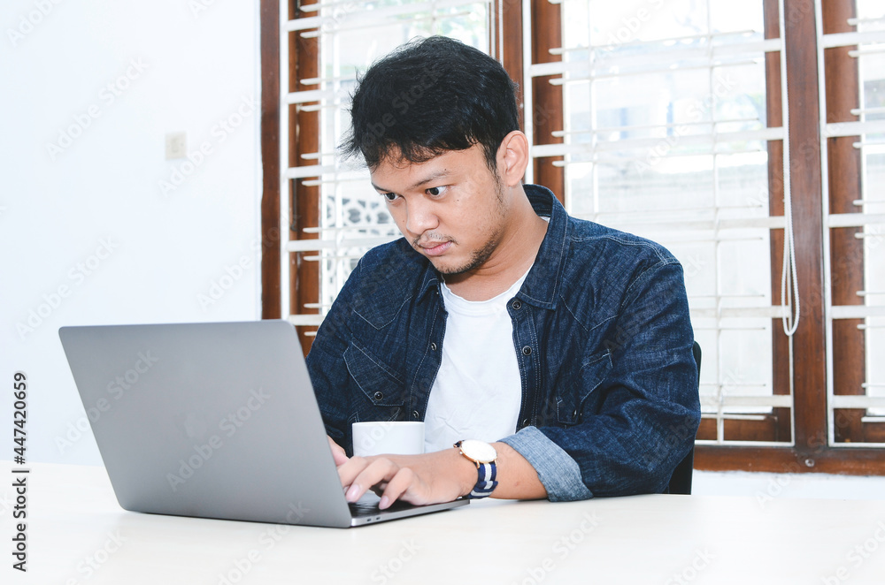 Fototapeta premium Young Asian man feeling serious when work laptop on table.
