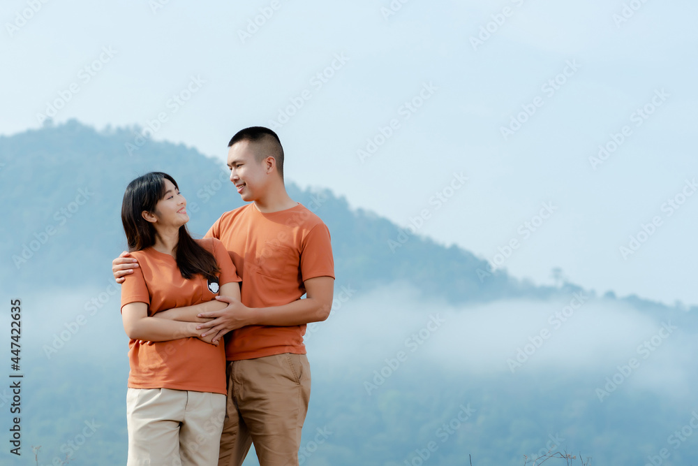 Portrait An Asian couple in identical brown shirts cuddling happily against a foggy and mountain backdrop. Portrait An Asian couple in identical brown shirts cuddling happily against a foggy and mountain backdrop.