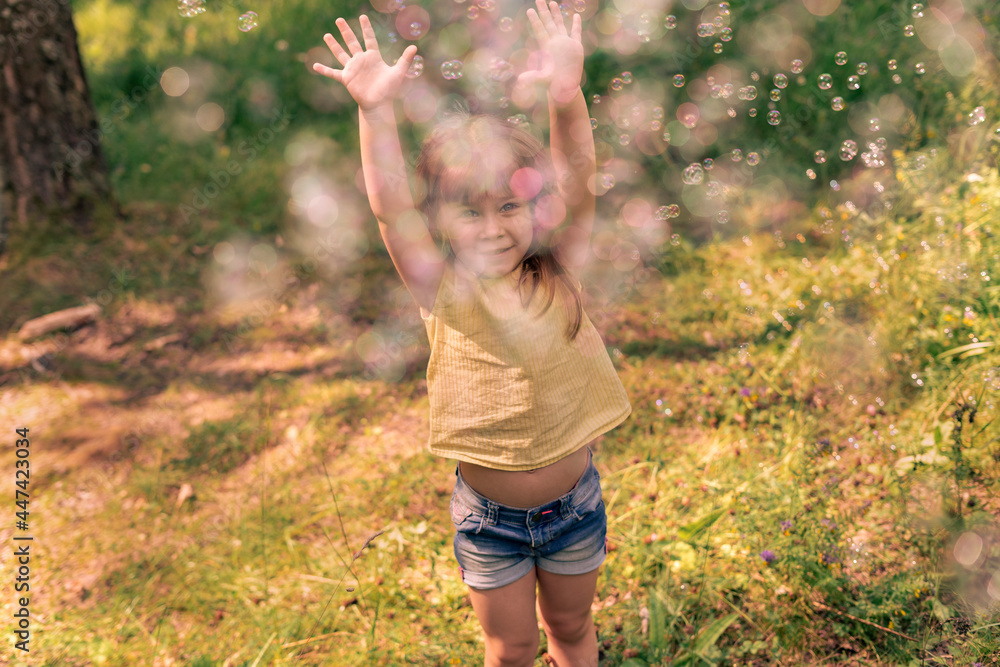 cute kid girl catches a lot of soap bubbles on a summer day, child in blur - obrazy, fototapety, plakaty 