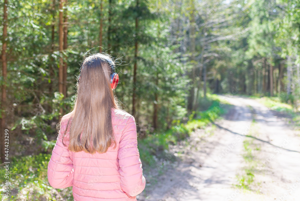 One lovely slim fit thin teen girl enjoying, listening to music in the forest while walking spring day forest or park. One lovely slim fit thin teen girl enjoying, listening to music in the forest while walking spring day forest or park.