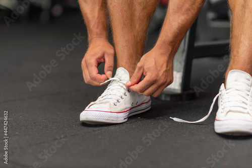 Sport man tying his shoelaces before a workout in a gym.Cropped image.