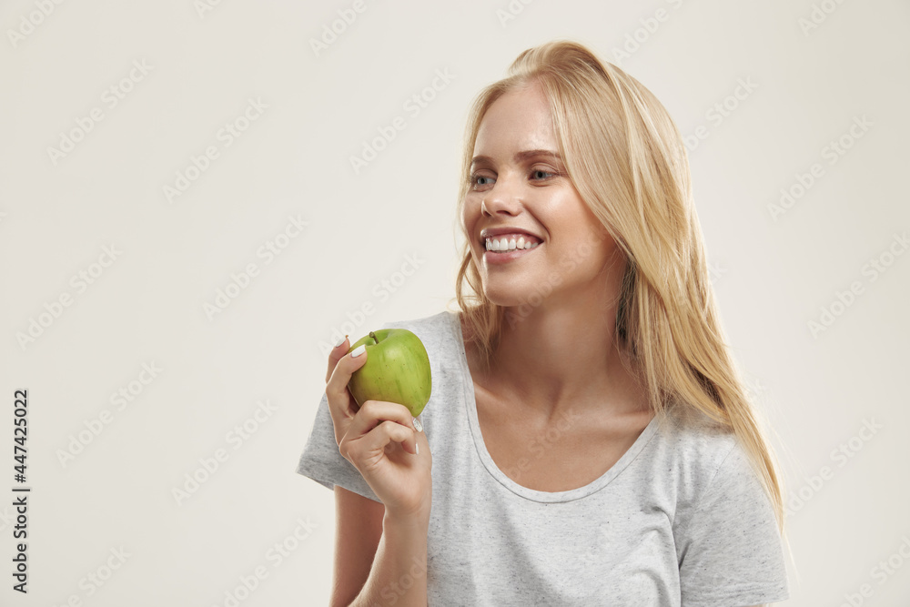 Young pleased european girl holding green apple Young pleased european girl holding green apple