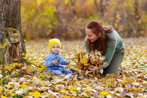 Happy family mother and baby laugh with leaves in nature autumn 