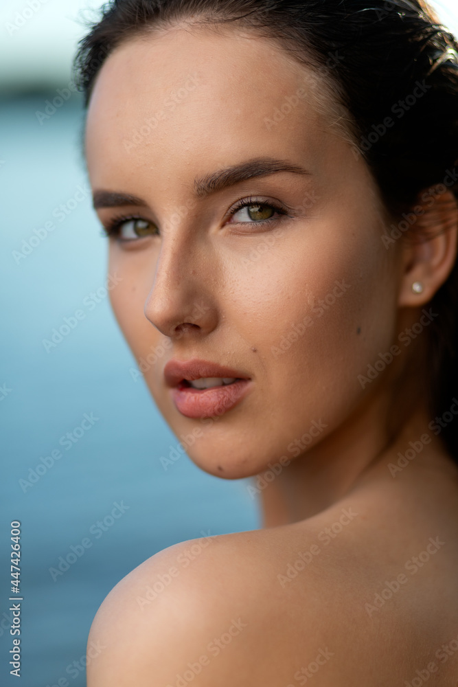 Naklejka premium Portrait of a beautiful woman with wet hair against the backdrop of the sea and sunset. fashionable stylish young woman on tropical beach