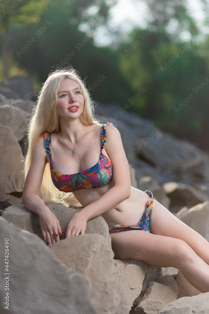 Obraz premium Beautiful woman with healthy body wearing in a colotful swimsuit ander wall.The concept of summer fashion swimsuit and relaxation
