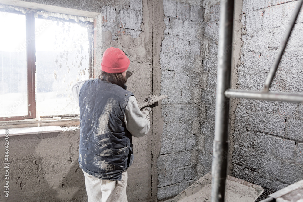Real construction worker working on a wall inside the new house. Real construction worker working on a wall inside the new house.