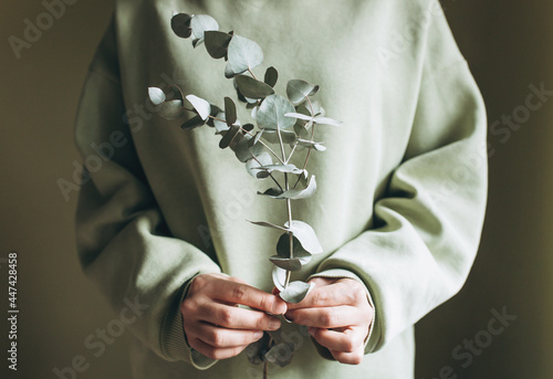 A woman holds a sprig of eucalyptus in her hands. The concept of environmental friendliness
