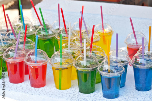 Multicolored fruit drinks close-up. Non-alcoholic drinks in plastic cups at the festival. Cocktails with juice and greens.