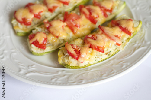 zucchini stuffed with fish with rice and cheese, garnished with tomatoes