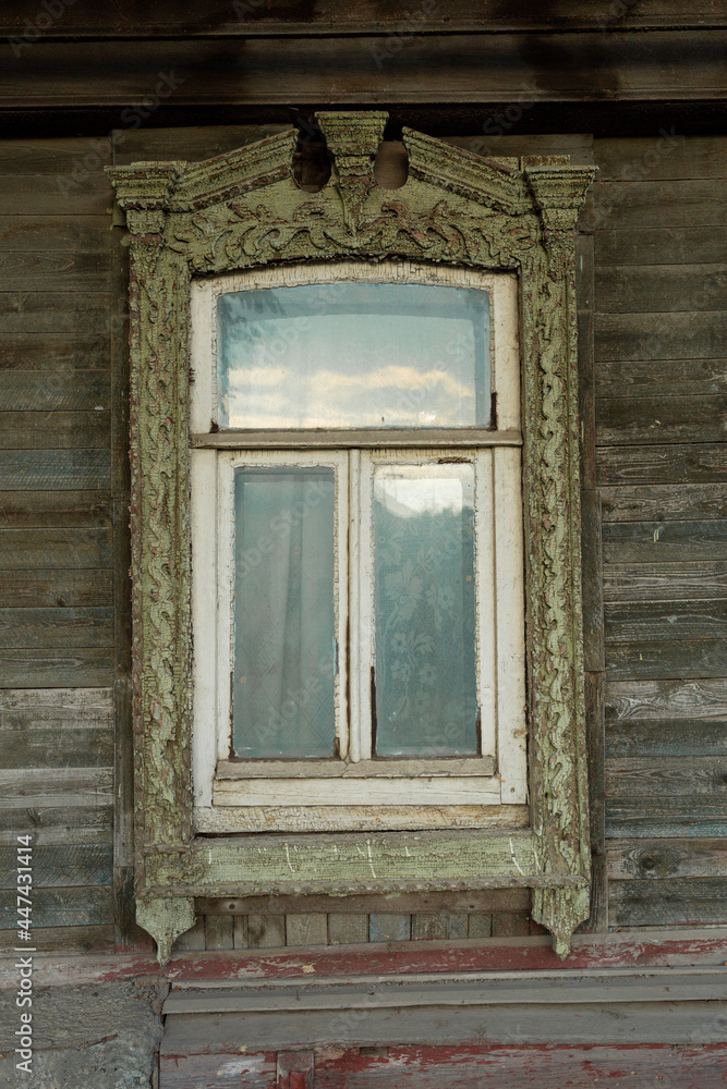 Fototapeta premium The window of an old wooden Russian house with beautiful decorative wood trims.