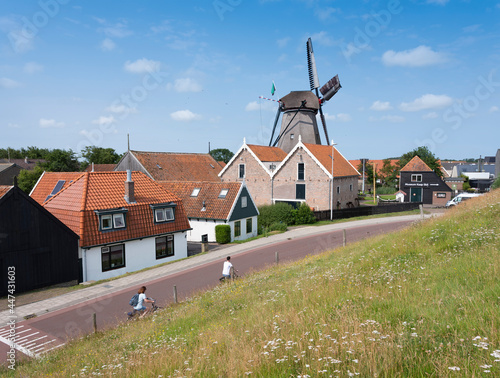 Valokuva village of oudeschild with windmill on dutch island of texel seen from dike