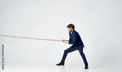 business man in a suit pulls the rope studio light background