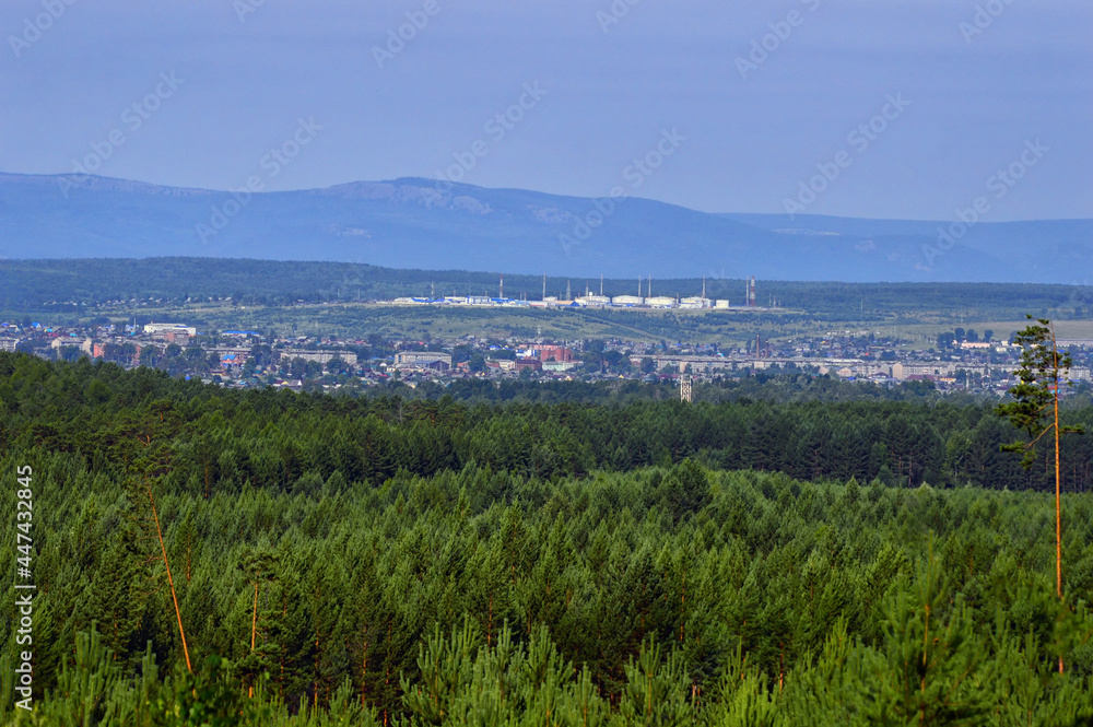 Panoramic view of the small town in Russia, Eastern Siberia. There is a dense green pine forest around it. Summer landscape