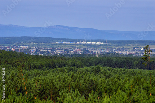 Panoramic view of the small town in Russia, Eastern Siberia. There is a dense green pine forest around it. Summer landscape