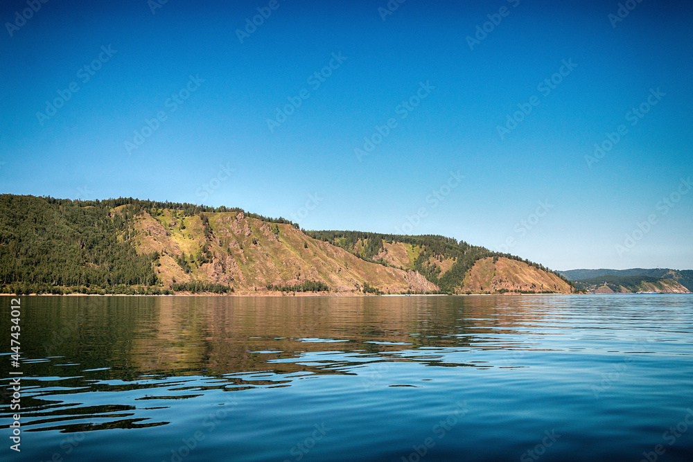 A beautiful natural landscape with a lake, shore and rocks in summer, warm sunny weather.