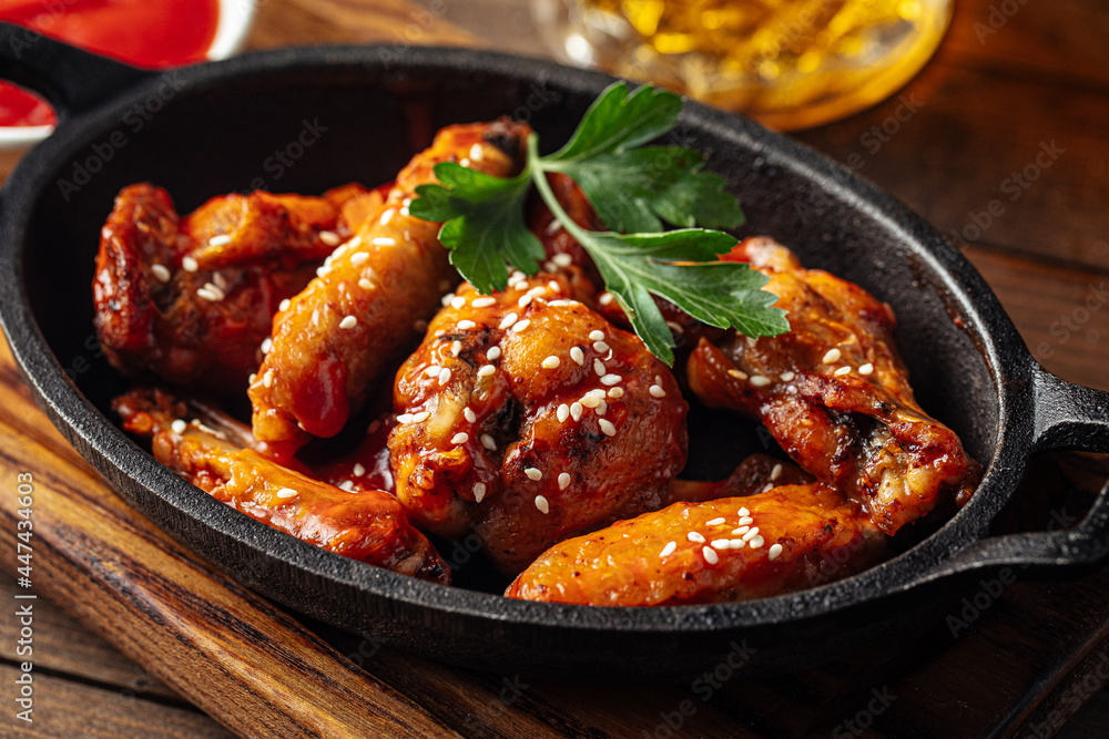 Cast iron plate of fried chicken wings in teriyaki sauce Cast iron plate of fried chicken wings in teriyaki sauce