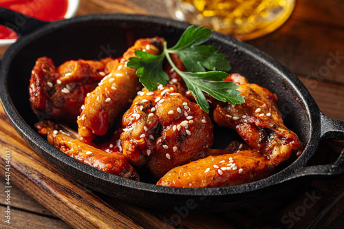 Cast iron plate of fried chicken wings in teriyaki sauce