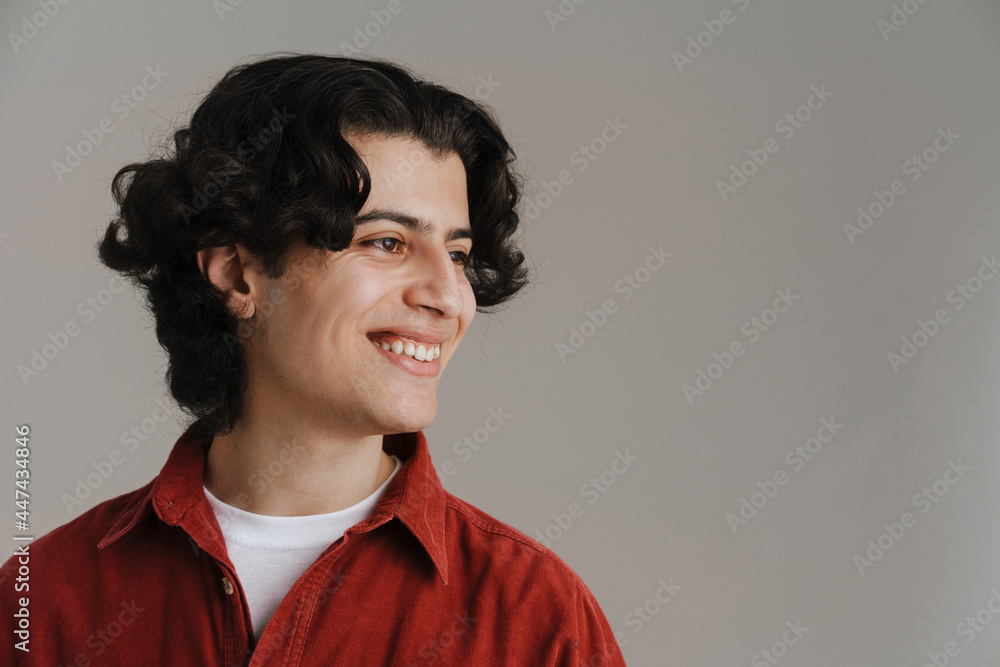 Obraz premium Young brunette man in red shirt smiling and looking aside