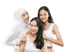 three happy asian women in white clothes smiling while looking at the camera over gray background