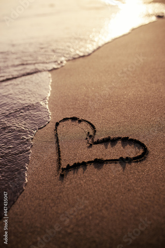 Heart symbol on a sand of beach at sunset