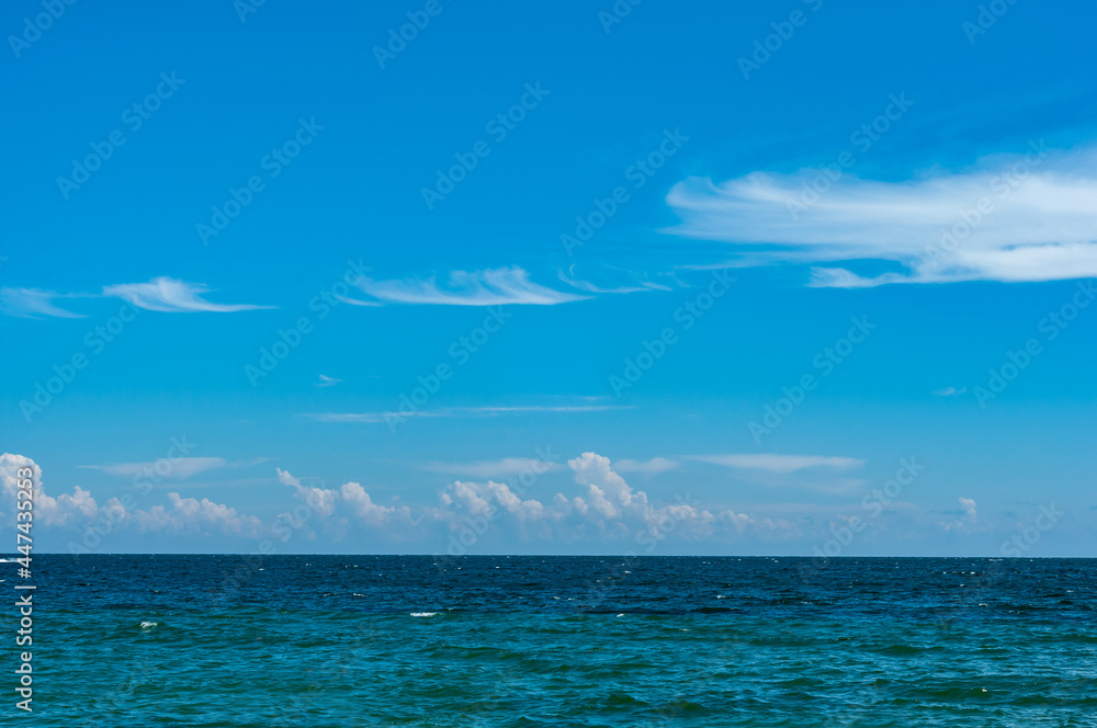 Calm sea with azure blue water, horizon line. Blue sky with cirrus clouds Calm sea with azure blue water, horizon line. Blue sky with cirrus clouds