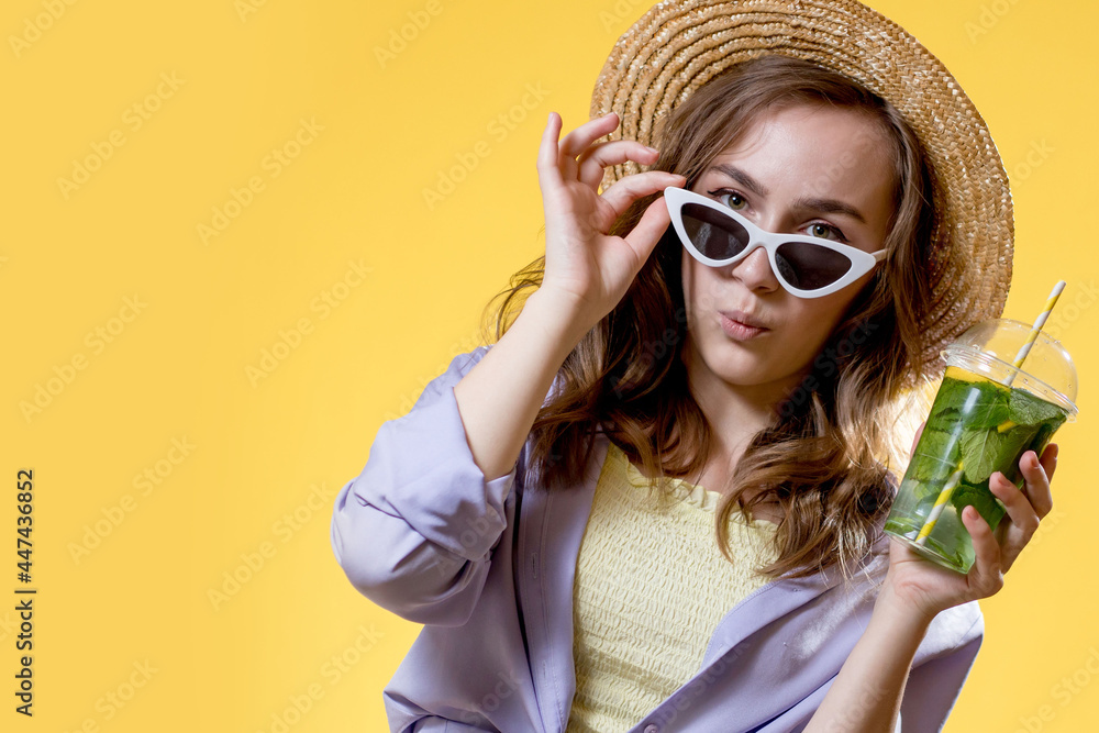 Fototapeta premium Surprised Woman Drink Mojito cocktail From Plastic Cup Over Yellow Studio Background