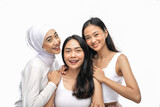 Smiling a veiled girl and two asian young girl stand next to each other in front of camera