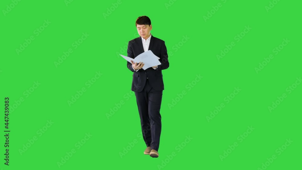 Asian businessman walks with documents looking at object on a Green Screen, Chroma Key. Asian businessman walks with documents looking at object on a Green Screen, Chroma Key.