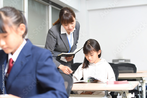 授業中に勉強をする女子学生と塾講師のイメージ photo