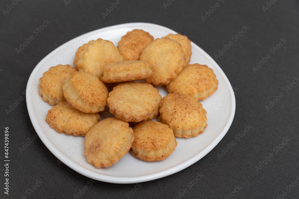 Homemade shortcrust pastry cookies on white plate. Baking for tea. Appetizing cookies. Gray background.