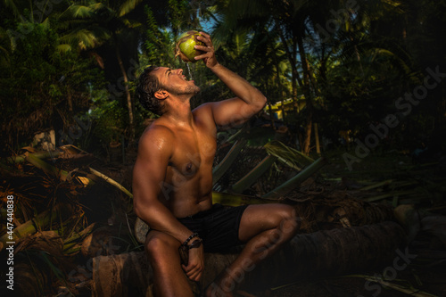 Young man on vacations sitting a palm tree and drinking coconut
