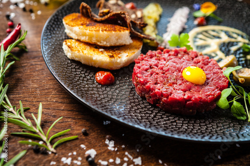 Beef tartare from Black Angus. Onion, quail egg, tomato sauce, mustard mayonnaise. Delicious healthy Italian traditional food closeup served for lunch in modern gourmet cuisine restaurant