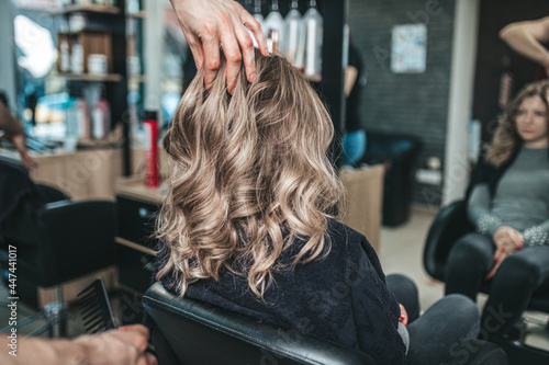 Beautiful hairstyle of woman after dyeing hair and making highlights in hair salon.