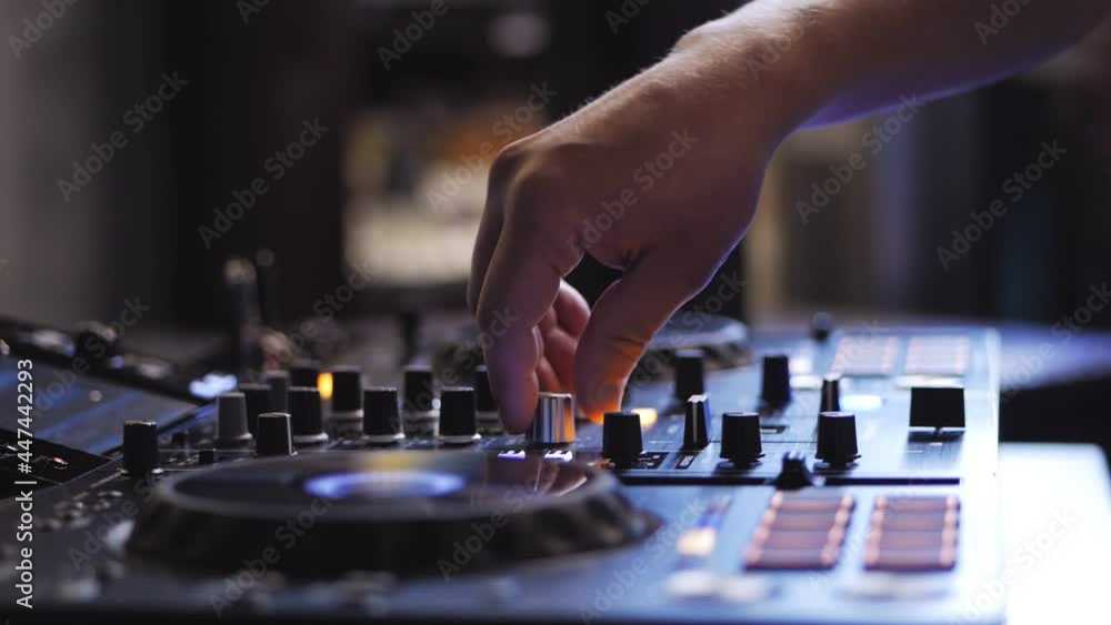 The DJ at the disco is working behind the remote control. Close-up of the DJ's hands on the control panel The DJ at the disco is working behind the remote control. Close-up of the DJ's hands on the control panel