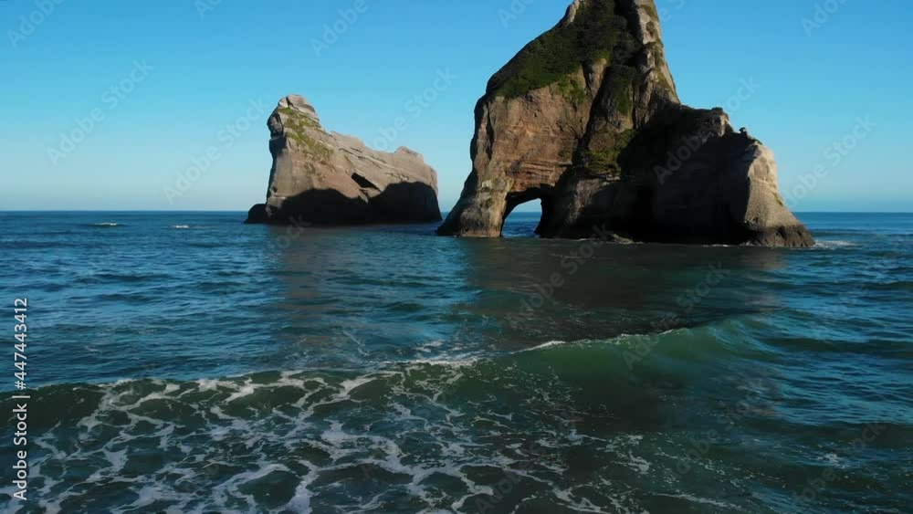 Waves breaks on New Zealand coastal. Nature scenery of picturesque location, sandy beach and spectacular rock archway formations. Aerial drone pull back Waves breaks on New Zealand coastal. Nature scenery of picturesque location, sandy beach and spectacular rock archway formations. Aerial drone pull back