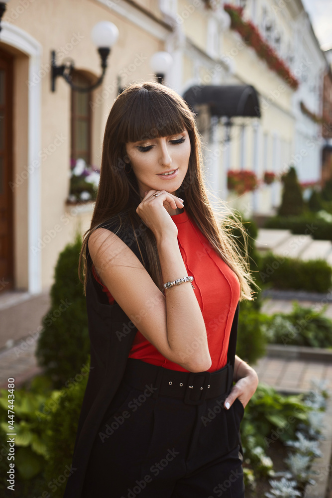 Portrait of a young woman with bright makeup in an elegant outfit on the city street