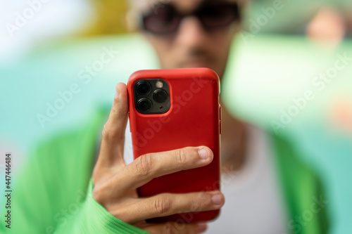 Chico sujetando smartphone con funda roja photo