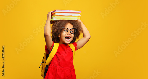 funny smiling Black child school girl with glasses hold books on her head photo