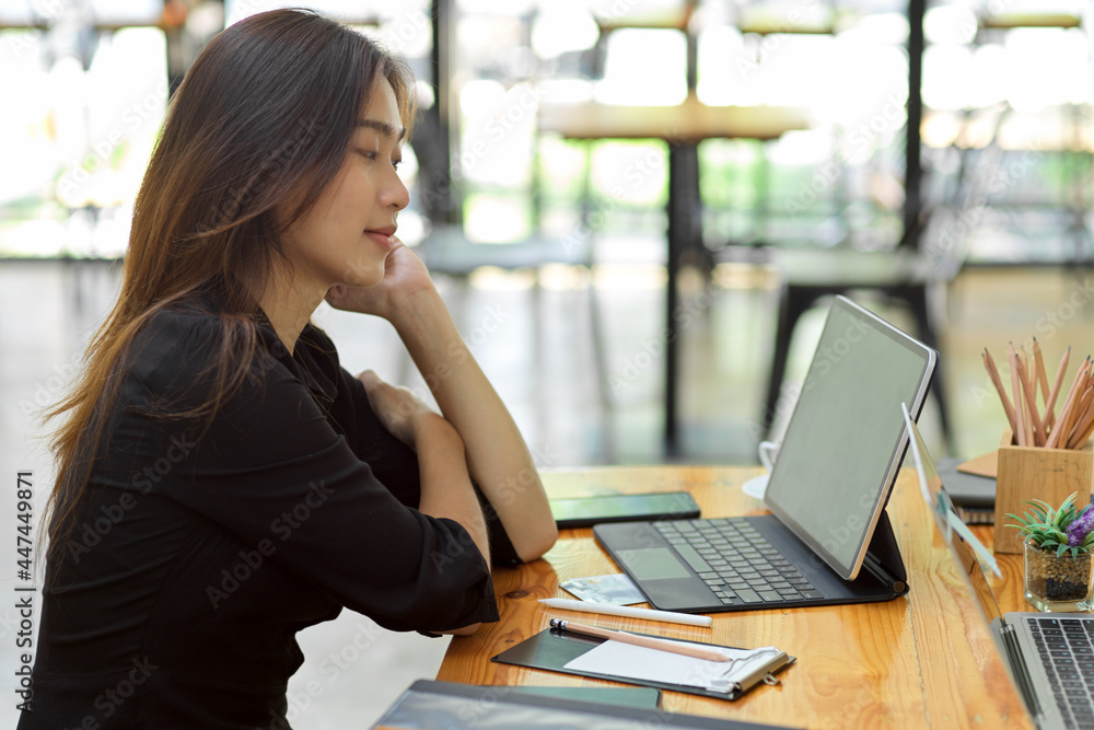 Fototapeta premium Attractive woman thinking about her job with smart tablet at coffee shop co-working area